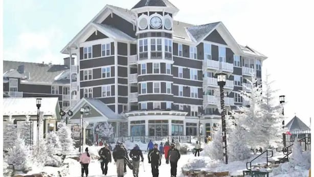 A multi-story hotel with a distinctive clock tower, large windows, and a snow-covered environment. - 11 Powderidge, Snowshoe, WV - Slopeside Serenity (Snowshoe)