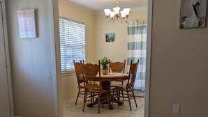 A dining area with a wooden table and chairs, a chandelier, and a painting on the wall.