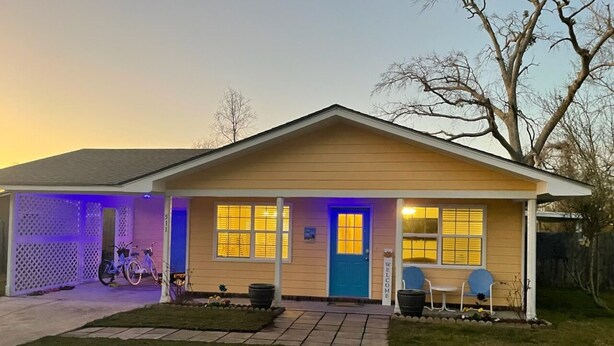 A single-story house with a garage, a front porch with two chairs, and a blue door.