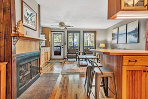 A kitchen with a fireplace, wooden cabinets, and a dining area with bar stools.