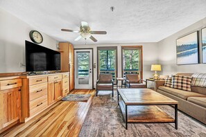 A well-lit living room with a television, wooden cabinets, a ceiling fan, a sofa, and a coffee table. - 24 Mountain Crest, Snowshoe, WV - Rustic Retreat (Snowshoe)