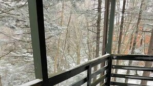 Uma área de estar coberta ao ar livre, com guarda-corpos de madeira e cadeiras cobertas de neve.