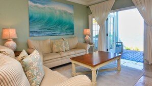 A living room with a large ocean wave painting, a sofa, a coffee table, and two lamps. - Indigo Reef Resort Villas and Marina (Marathon)
