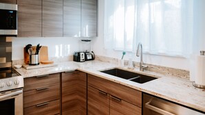 A modern kitchen with wooden cabinets, a stainless steel sink, and a built-in oven. - Modern Apt w/ Private Entry & Patio - Mtn Views (Smithfield)