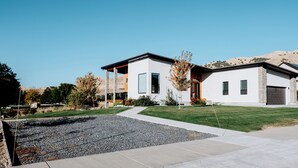 A modern two-story house with a large driveway, a small garden, and a clear blue sky. - Modern Apt w/ Private Entry & Patio - Mtn Views (Smithfield)