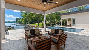 Un espace extérieur abrité, doté d’une piscine, de mobilier en bois et offrant une vue sur le lac.