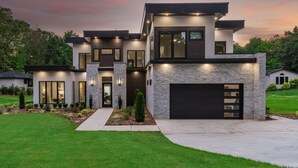 Une maison moderne à deux étages, dotée d’un garage, de grandes fenêtres et d’une pelouse bien entretenue.