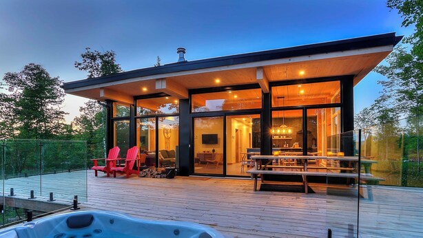 Une maison moderne dotée d’un patio entièrement vitré, d’un jacuzzi et d’un espace salon extérieur.