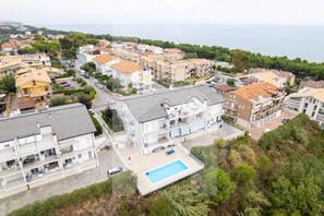 Zona residencial con varios edificios de apartamentos, una piscina y vista al mar.