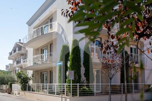 Un immeuble résidentiel à plusieurs étages, doté de balcons, d’une entrée sécurisée et surplombant un ciel dégagé.