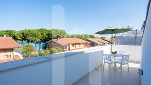 A balcony with a table and chairs, overlooking a residential area with trees and houses. - Mugo - Three-room apartment a few steps from the sea (Pineto)