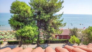 A beach with umbrellas, a tree, and a building in the background. - Pinetina Di Paolo - Second floor apartment, directly on the sea (Pineto)