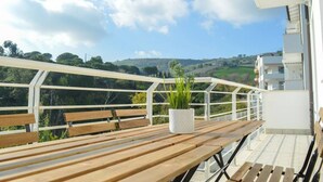 A balcony with a wooden table, a potted plant, and a white railing. - I Gabbiani 10 - Ali - Two-room apartment on second floor with balcony (Foggetta)