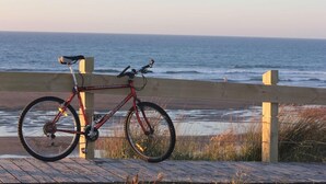 A red bicycle parked on a wooden boardwalk by the ocean. - Beach Street Motel Apartments (New Plymouth)