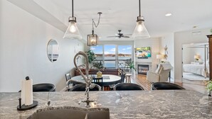 Una cocina moderna con encimera de mármol, luces colgantes y zona de comedor con vistas.