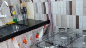 A kitchen with a gas stove, a sink, and a tiled backsplash. - Apartment (Jaboatão dos Guararapes)