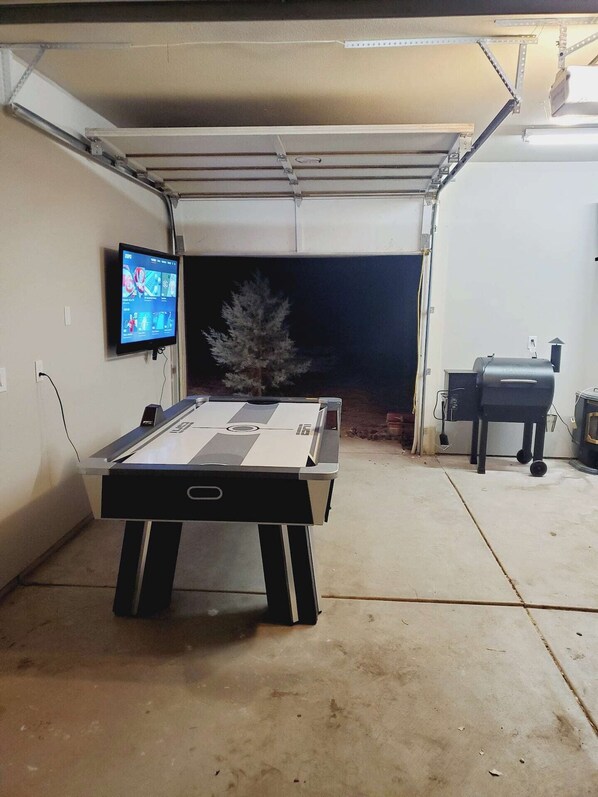 A table tennis table in a garage with a TV mounted on the wall. - Beautiful Mountain Cabin Getaway (Pinetop)