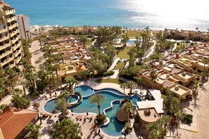 Un resort con piscina central, varias villas y zona de playa.