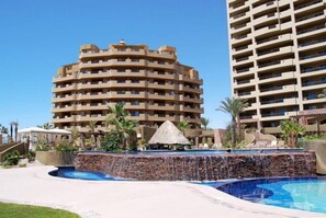 Um hotel com um edifício circular, piscina e estrutura com telhado de palha.