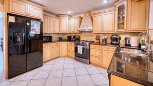 Una cucina con mobili in legno, un frigorifero in acciaio inox, un fornello e un lavandino.