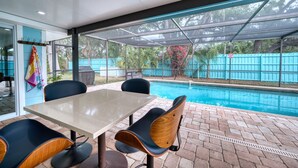 Un'area patio coperta con piscina, tavolo e sedie.