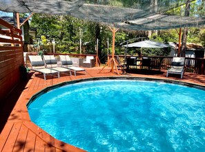 A swimming pool with lounge chairs and a wooden deck. - Stylish House with Pool 5BR/3BA (Raleigh)