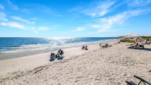A beach with people relaxing, a tent, and a mountain in the distance. - Direct beachfront! Best gulf views and sunsets! Pickleball and tennis!  (Fort Myers Beach)