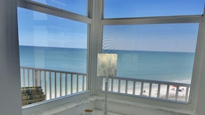 A white desk with a chair, a lamp, and a view of the beach through large windows. - Direct beachfront! Best gulf views and sunsets! Pickleball and tennis!  (Fort Myers Beach)