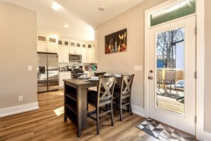 A modern kitchen with white cabinets, stainless steel appliances, and a dining area with dark wooden furniture.