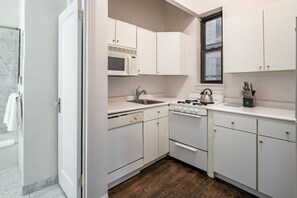 A compact kitchen with white cabinets, a microwave, a stove, and a sink.
