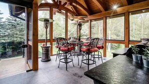 A wooden interior with a dining area, large windows, and a view of trees. - The Mansion, Wasaga beach, Blue mountain (Utopia)