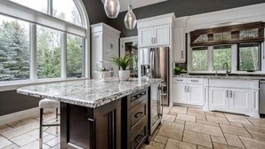 A modern kitchen with a large island, white cabinetry, and a view of the outdoors. - The Mansion, Wasaga beach, Blue mountain (Utopia)