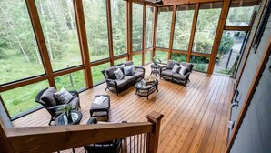 A spacious deck with wooden flooring and large windows offering a view of a forested area. - The Mansion, Wasaga beach, Blue mountain (Utopia)
