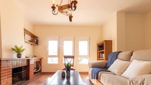 Una sala de estar con chimenea, un sofá, una mesa de centro y una estantería.