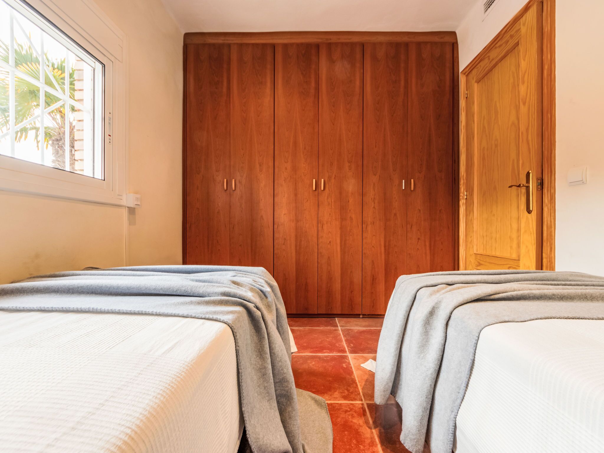 Un dormitorio con dos camas, armarios de madera y un ventanal.