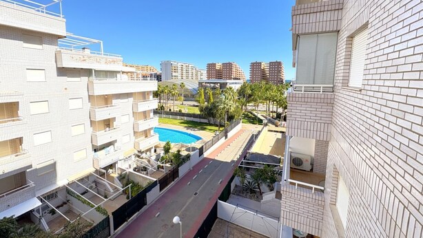 A residential building with multiple balconies, a swimming pool, and a clear view of the surrounding area.