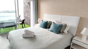 Une chambre d’hôtel avec un grand lit, une table de chevet, une lampe et une vue sur un balcon équipé d’une chaise et d’une table.