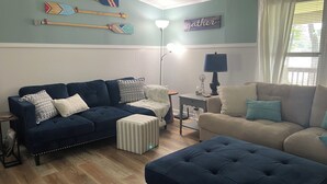 A living room with two sofas, a coffee table, and a lamp. There are decorative items on the wall and a window with curtains. - Quiet Cove with Big Water Views (Ridgeway)