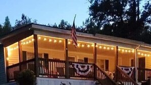 A two-story house with a porch, a flag, and string lights. - Quiet Cove with Big Water Views (Ridgeway)