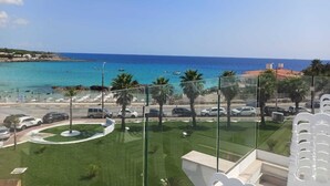 A view of a coastal area with a clear sky, a beach, and parked cars. - Jonium Hotel (Pulsano)