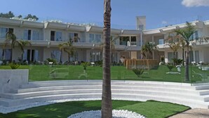 A modern hotel with a central courtyard, multiple balconies, and a well-maintained lawn. - Jonium Hotel (Pulsano)