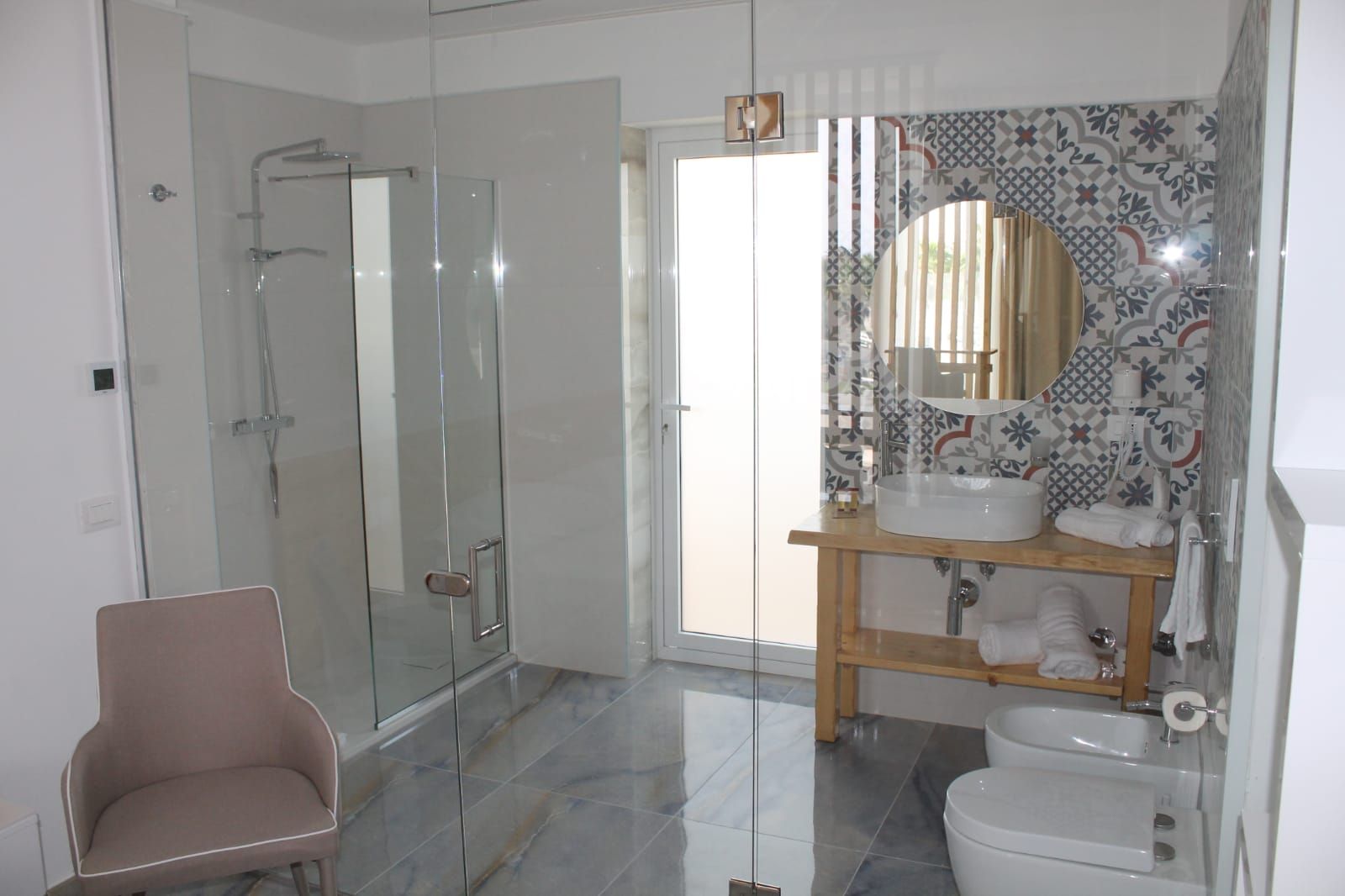 Un baño moderno con cabina de ducha de vidrio, tocador con espejo y un inodoro.