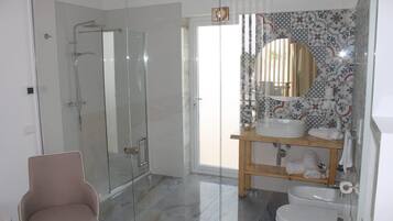 Un baño moderno con cabina de ducha de vidrio, tocador con espejo y un inodoro.