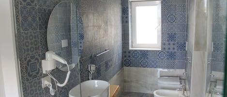 A bathroom with patterned tiles, a round sink, a toilet, and a window.