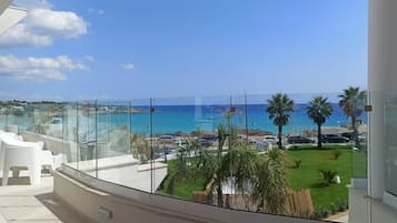Un balcón con vistas despejadas al mar, palmeras y una zona verde.