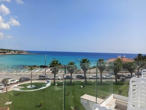 A view of a coastal area with a clear sky, a beach, and parked cars. - Jonium Hotel (Pulsano)