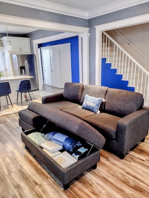 Relax in this stylish living room with a sofa, kitchen area, and staircase leading to an upper level.
