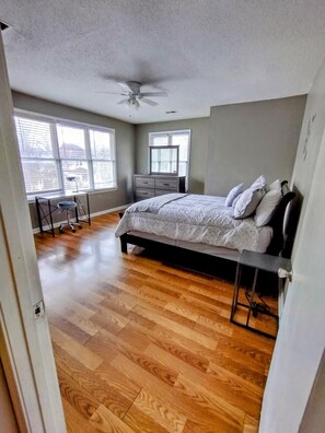 Relax in this serene bedroom with a large bed, ceiling fan, and dresser.