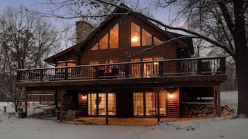 Enjoy the expansive views from the upper balcony of this cozy cabin, surrounded by a serene snowy landscape.