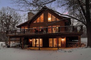 Enjoy the expansive views from the upper balcony of this cozy cabin, surrounded by a serene snowy landscape.